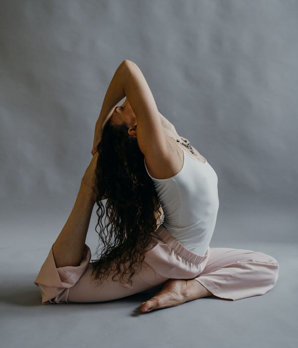 Woman in a calm warrior yoga pose in a studio with soft lighting.